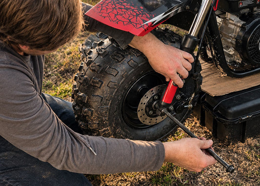 Man holding tool at front of FatCat Mini Bike doing bike maintenance
